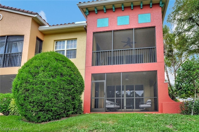 rear view of house featuring a sunroom and a yard