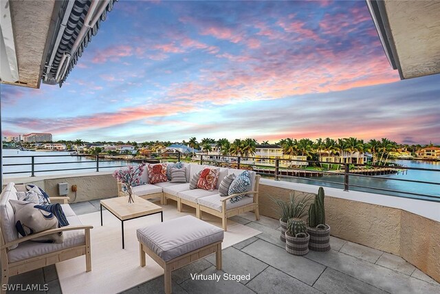 patio terrace at dusk with a water view, a balcony, and an outdoor hangout area