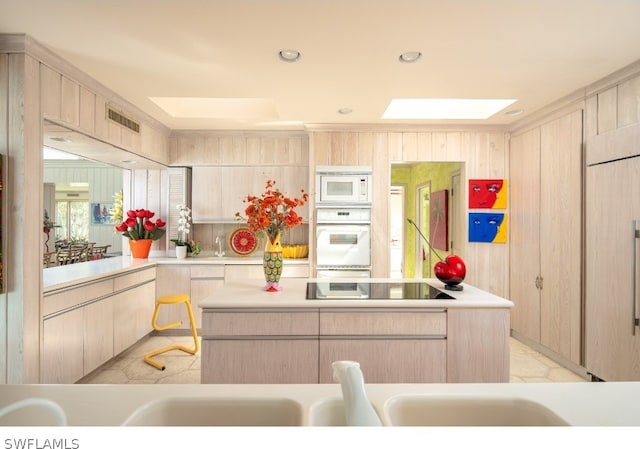 kitchen featuring a skylight, light brown cabinets, white appliances, and light tile flooring