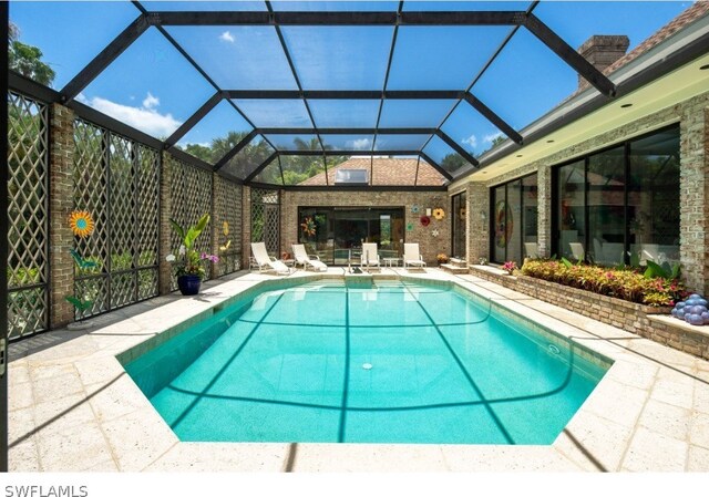 view of swimming pool featuring glass enclosure and a patio area