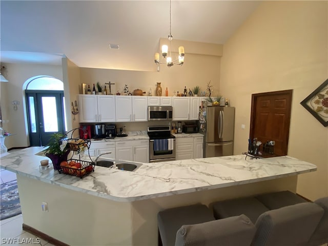 kitchen with hanging light fixtures, white cabinets, stainless steel appliances, a notable chandelier, and sink