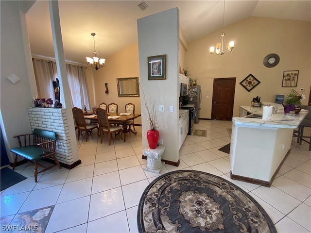 interior space featuring decorative light fixtures, light tile floors, and vaulted ceiling