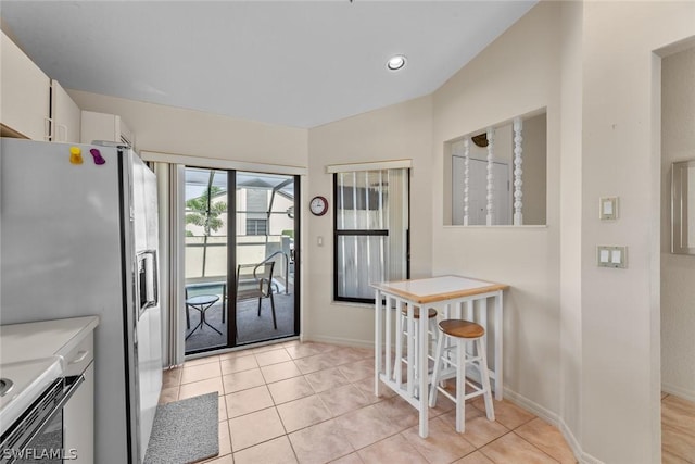 kitchen with white cabinets, light tile patterned flooring, and white refrigerator with ice dispenser