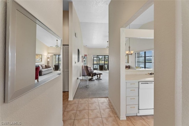 hallway featuring light carpet, a textured ceiling, vaulted ceiling, and a healthy amount of sunlight