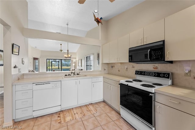 kitchen with white appliances, vaulted ceiling, sink, light tile patterned floors, and decorative light fixtures