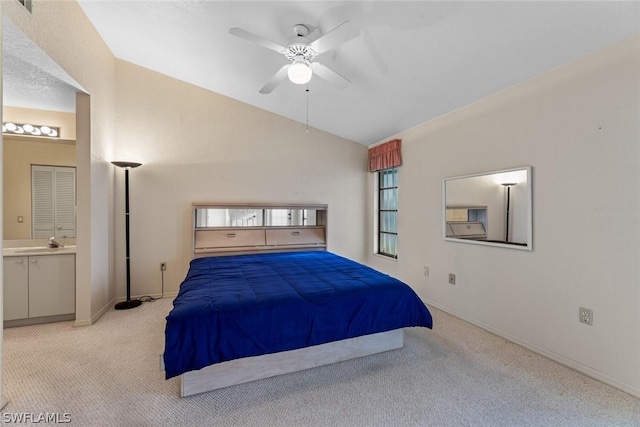 bedroom featuring ensuite bath, light colored carpet, ceiling fan, sink, and lofted ceiling