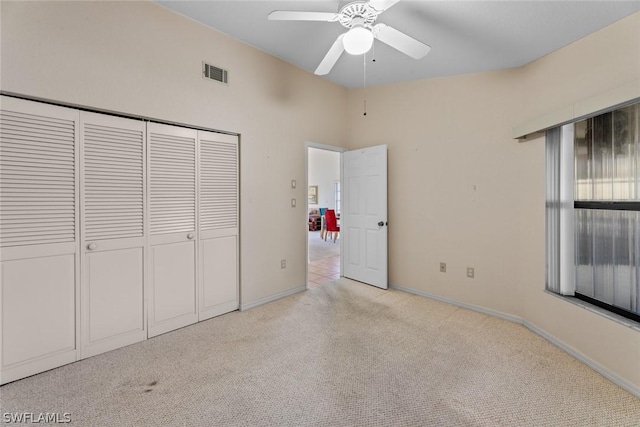 unfurnished bedroom featuring ceiling fan, light colored carpet, multiple windows, and a closet