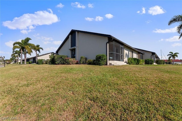 view of home's exterior with a sunroom and a yard