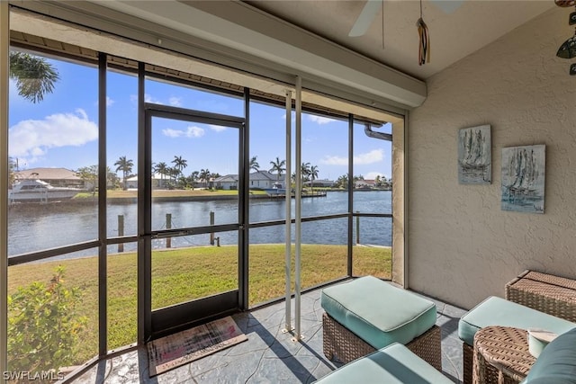 sunroom / solarium featuring a water view and ceiling fan