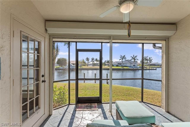 unfurnished sunroom with ceiling fan, a water view, and a wealth of natural light