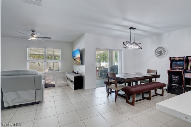 tiled dining area featuring ceiling fan with notable chandelier