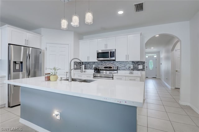 kitchen featuring white cabinetry, stainless steel appliances, sink, light tile floors, and a center island with sink