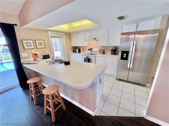 kitchen featuring a kitchen bar, sink, white cabinets, stainless steel appliances, and kitchen peninsula