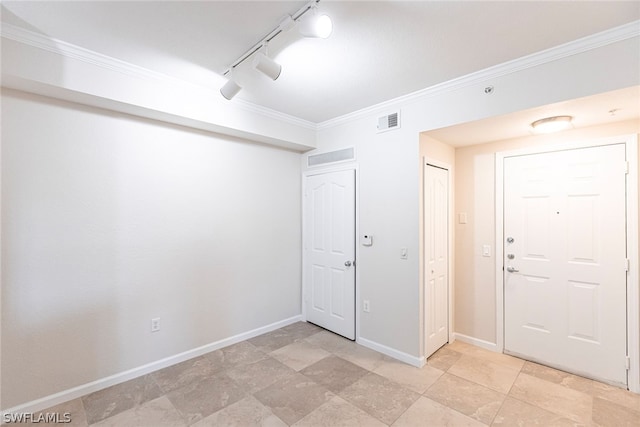 tiled entryway featuring rail lighting and crown molding