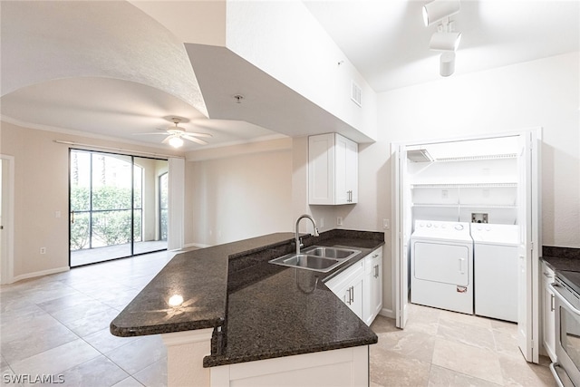 kitchen featuring ceiling fan, independent washer and dryer, dark stone counters, rail lighting, and sink