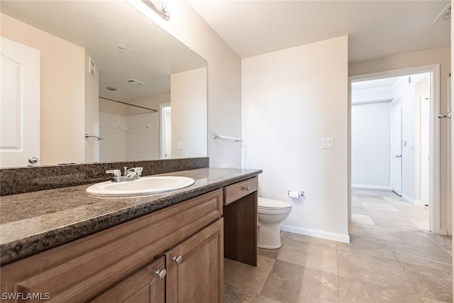 bathroom featuring vanity with extensive cabinet space, toilet, and tile floors