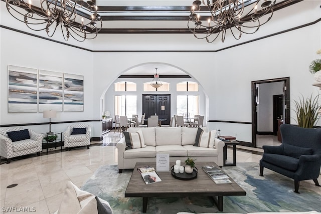 living room featuring a towering ceiling, crown molding, light tile flooring, and a chandelier