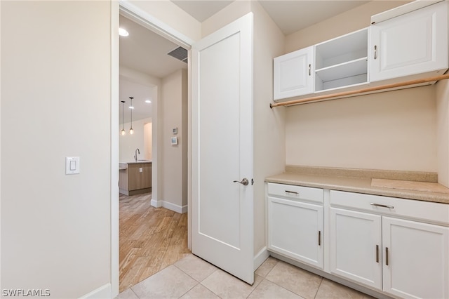 interior space featuring sink, pendant lighting, light wood-type flooring, and white cabinetry