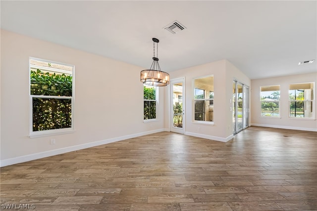 empty room with hardwood / wood-style floors and a notable chandelier