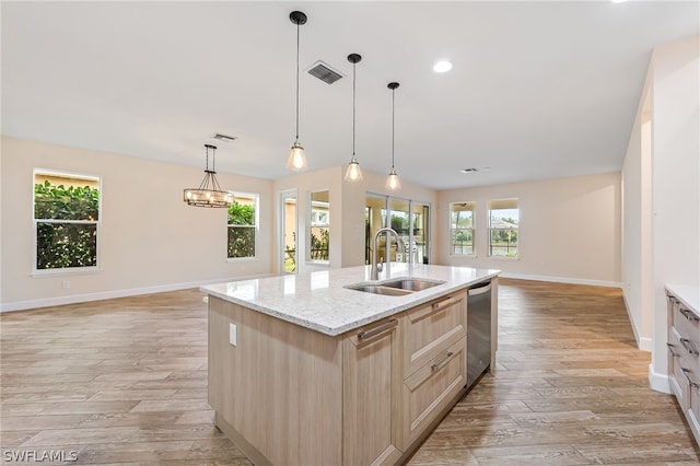 kitchen featuring hanging light fixtures, a kitchen island with sink, light wood-type flooring, light brown cabinets, and sink