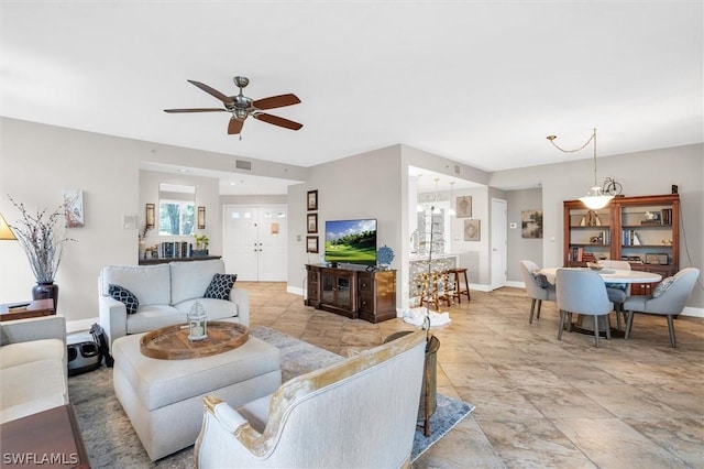 living room with ceiling fan with notable chandelier