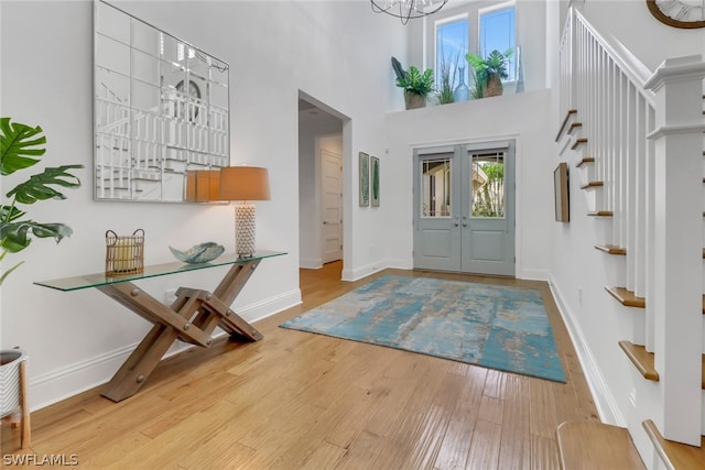 entryway featuring an inviting chandelier, a high ceiling, and light hardwood / wood-style flooring