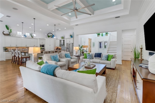 living room featuring beam ceiling, ceiling fan, light hardwood / wood-style flooring, and a high ceiling