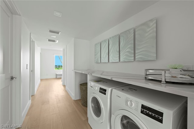 laundry room with washer and dryer and light wood-type flooring