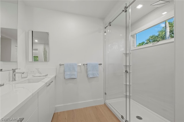 bathroom featuring wood-type flooring, an enclosed shower, and dual vanity