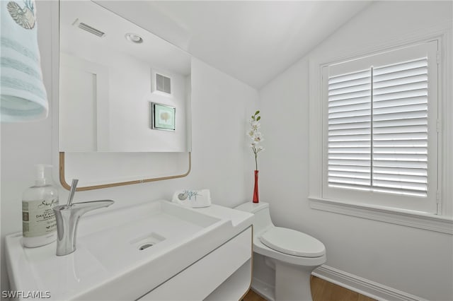 bathroom with wood-type flooring, vanity, a wealth of natural light, toilet, and lofted ceiling