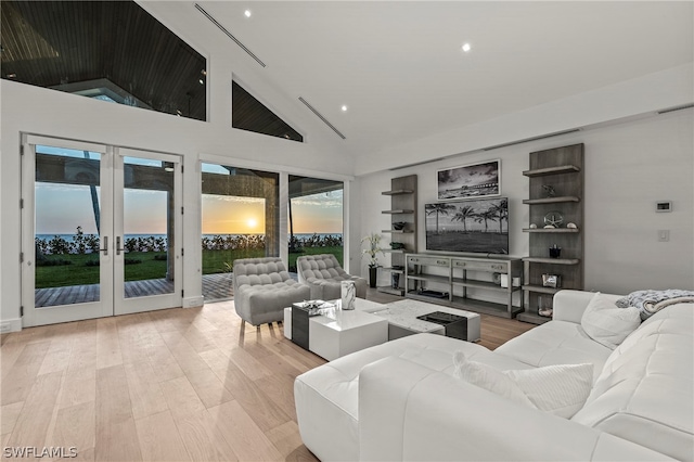 living room with high vaulted ceiling, french doors, and light wood-type flooring