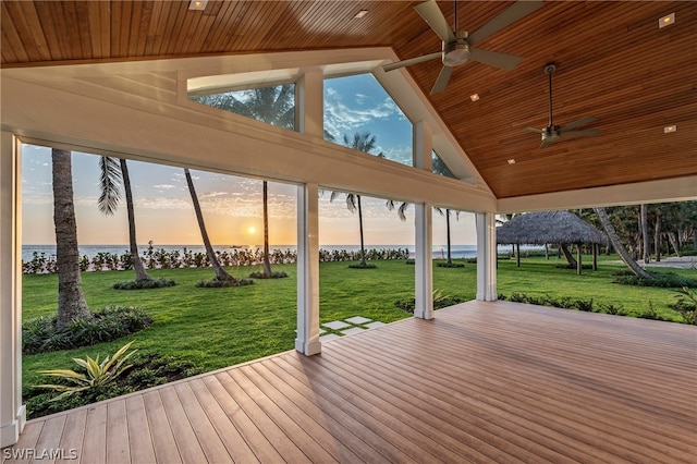 deck at dusk featuring a yard, a water view, and ceiling fan