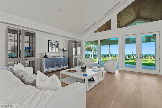 living room with high vaulted ceiling, french doors, and light hardwood / wood-style flooring