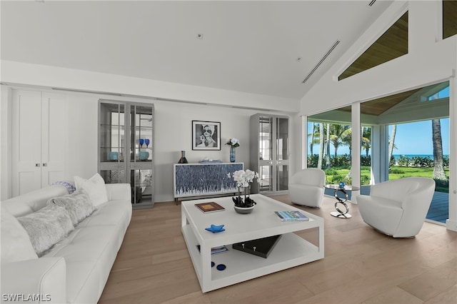 living room with high vaulted ceiling, light hardwood / wood-style flooring, and french doors