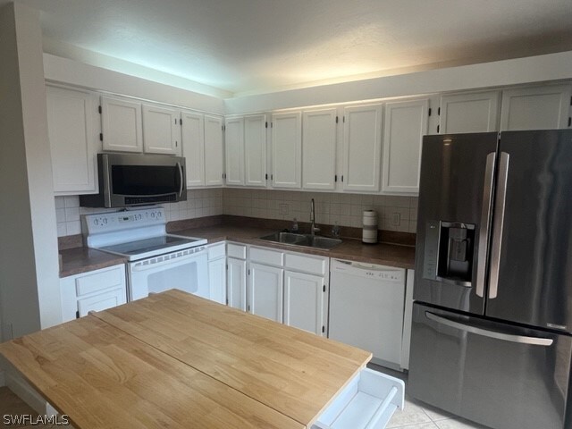 kitchen with backsplash, white cabinets, white appliances, and sink