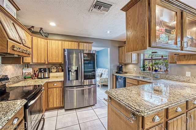 kitchen featuring light tile patterned flooring, sink, light stone counters, a textured ceiling, and appliances with stainless steel finishes