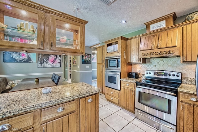 kitchen featuring decorative backsplash, light tile patterned floors, stainless steel appliances, light stone countertops, and a textured ceiling