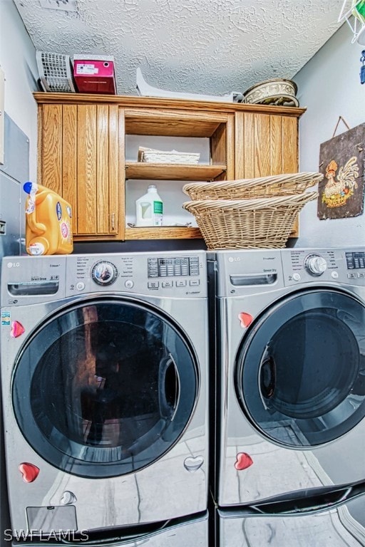 laundry area featuring washer and clothes dryer, cabinets, and a textured ceiling