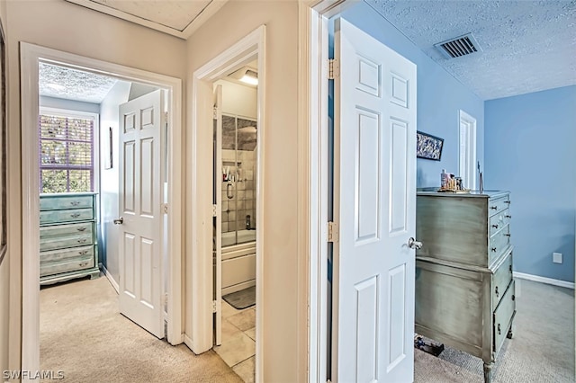 hall with light colored carpet and a textured ceiling