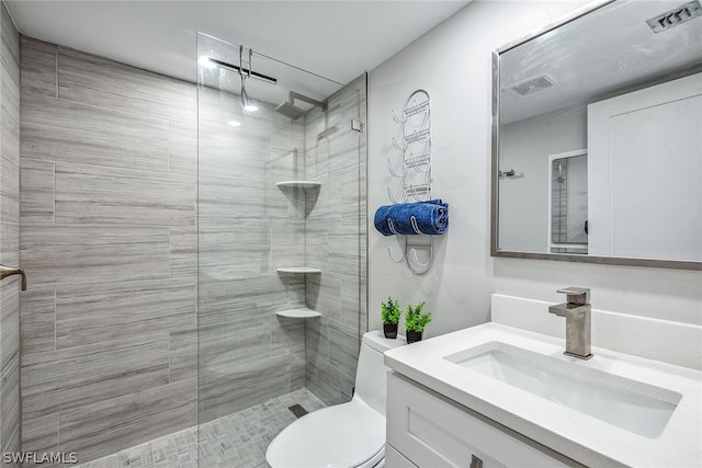 bathroom with tiled shower, vanity, and toilet