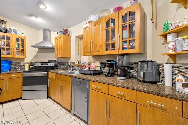 kitchen with light tile floors, sink, wall chimney range hood, stainless steel electric range oven, and dark stone countertops