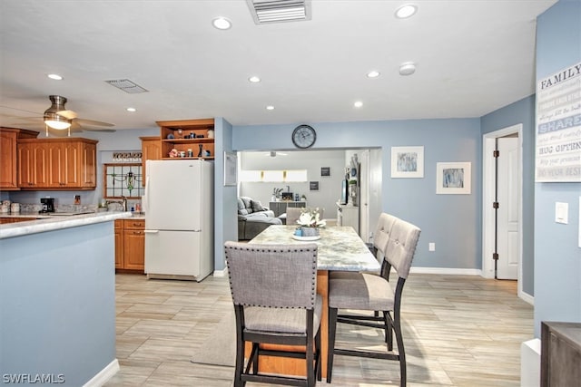 kitchen featuring ceiling fan, white fridge, and a kitchen bar