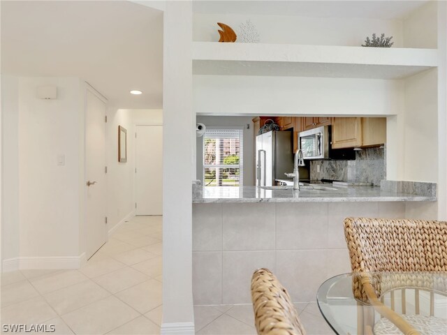 kitchen featuring light tile patterned floors, sink, stainless steel appliances, light brown cabinetry, and light stone countertops