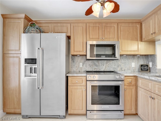 kitchen with appliances with stainless steel finishes, light stone countertops, light brown cabinetry, and tasteful backsplash