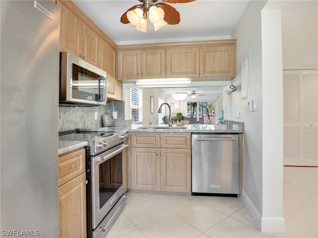 kitchen featuring appliances with stainless steel finishes, light stone counters, tasteful backsplash, light tile patterned floors, and sink