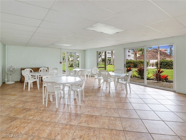 unfurnished dining area featuring a drop ceiling, light tile patterned floors, and a wealth of natural light