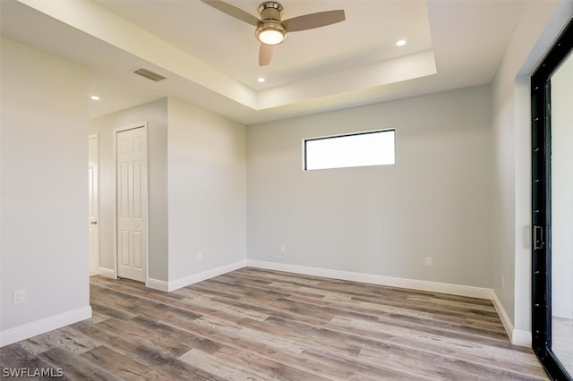 spare room featuring a raised ceiling, ceiling fan, and hardwood / wood-style flooring