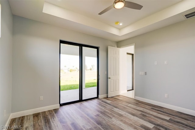 spare room with ceiling fan, hardwood / wood-style floors, and a tray ceiling