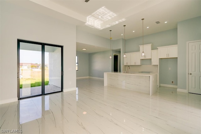 empty room with sink, a high ceiling, and light tile floors