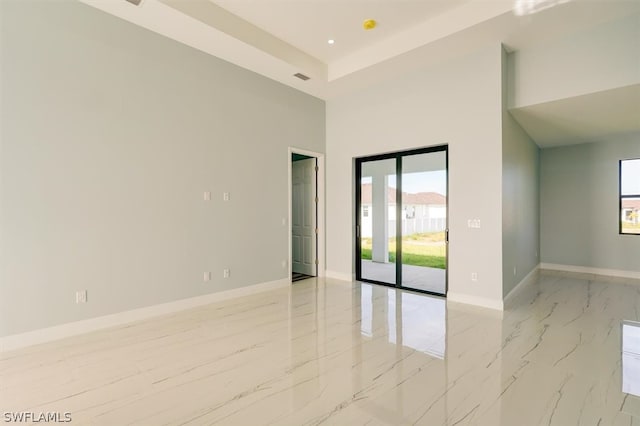 tiled spare room featuring a towering ceiling